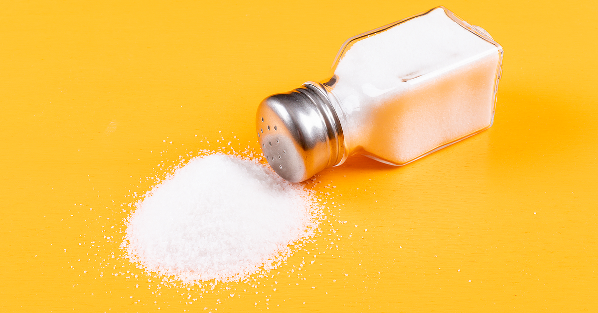 Salt shaker near a pile of salt.