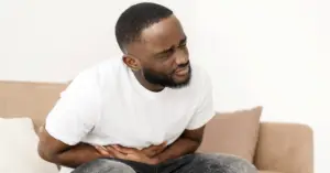 African man clutching stomach in pain.