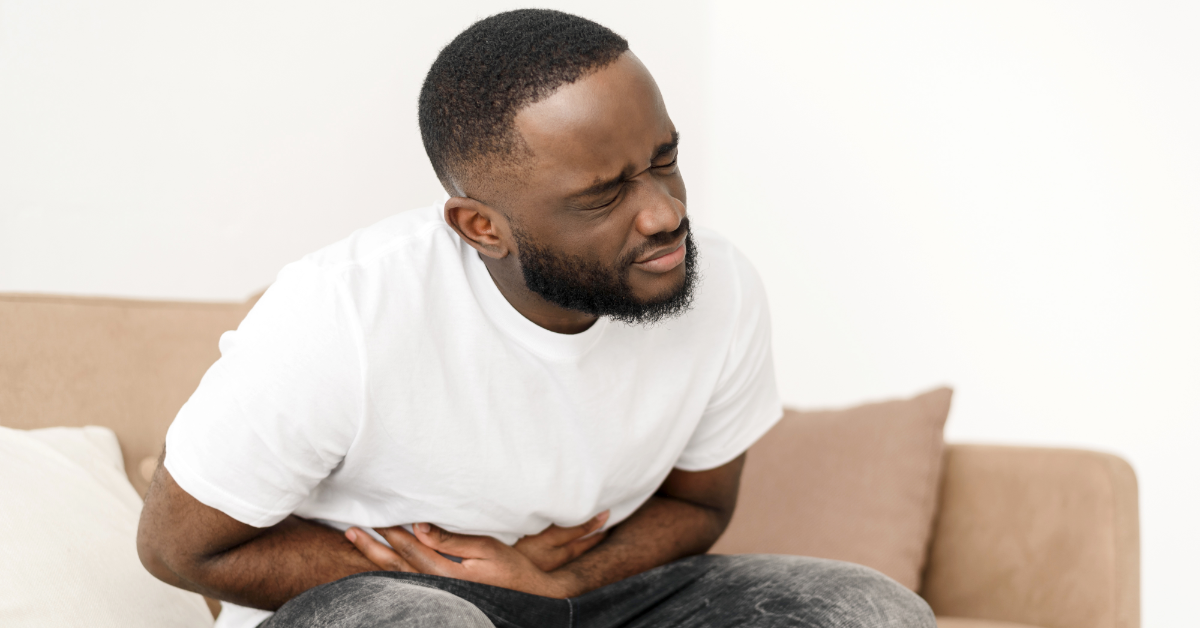 African man clutching stomach in pain.